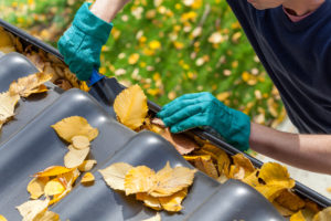 Man-Cleaning-Gutters-Removing-Leaves